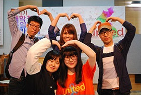 united 배너 앞에서 손으로 하트를 만든 참가자들