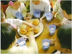 식탁에 둘러앉아 빵과 우유를 먹는 북녘 어린이들